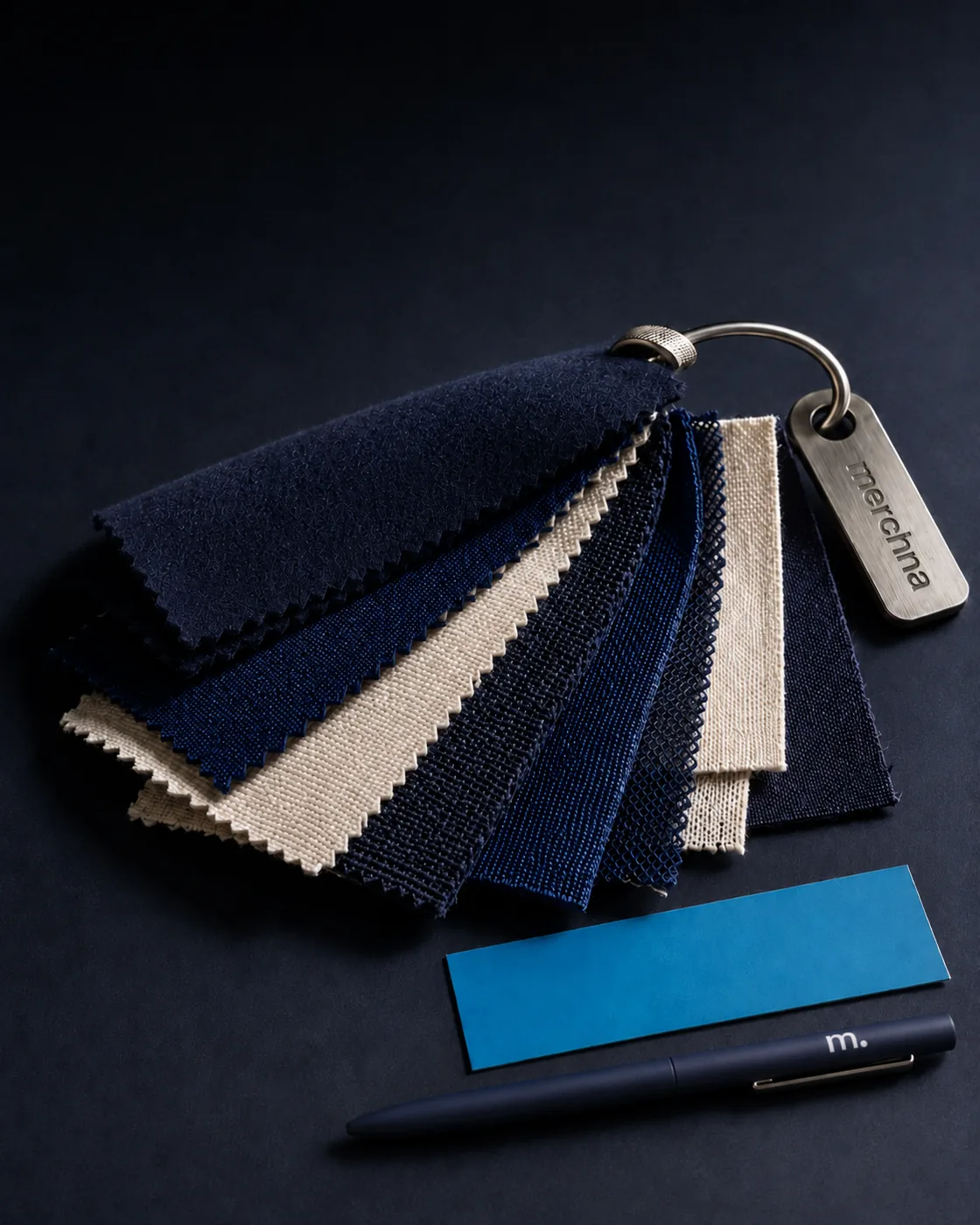 A Merchna fabric swatch ring fanned open beside a colour chip and a pen