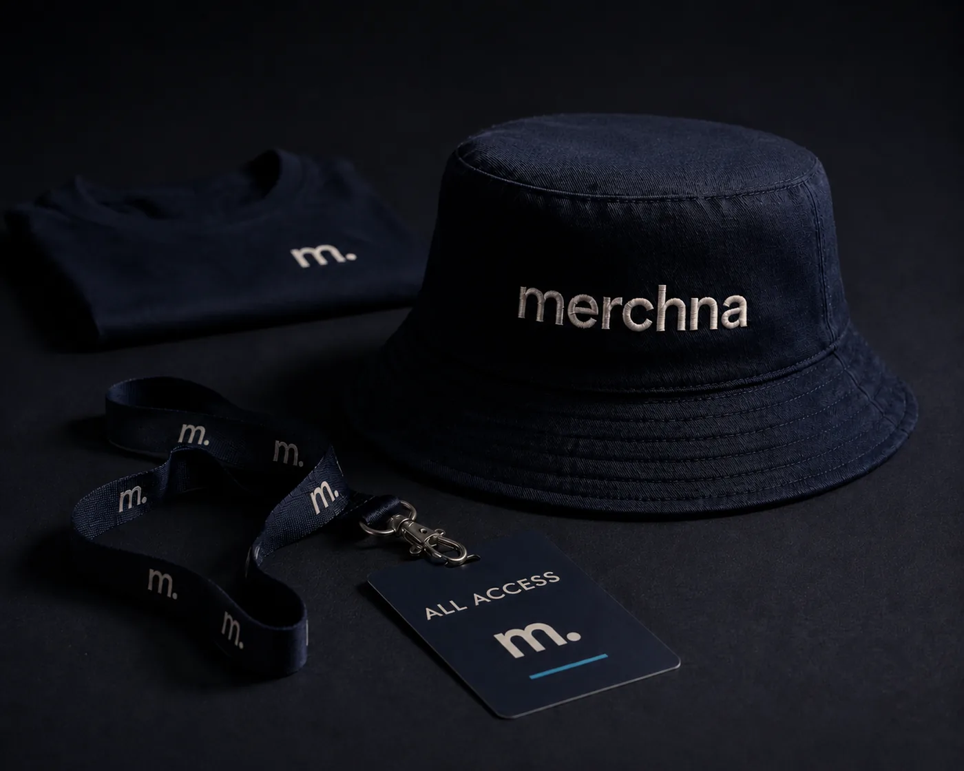 Merchna event merch: a navy bucket hat, a folded tee and an all-access lanyard pass